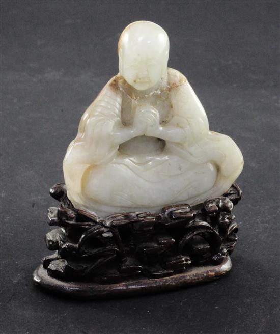 A Chinese white and russet jade carving of a luohan, 18th / 19th century, 6.7cm, neck broken and restuck, intricately carved rosewood s